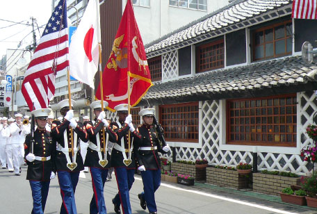 下田黒船祭のパレードで旗を掲げる制服の人々
