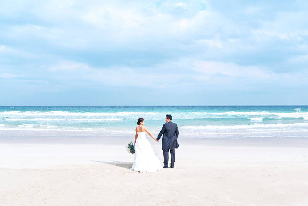 白浜の海に向かって手をつなぐ新郎新婦